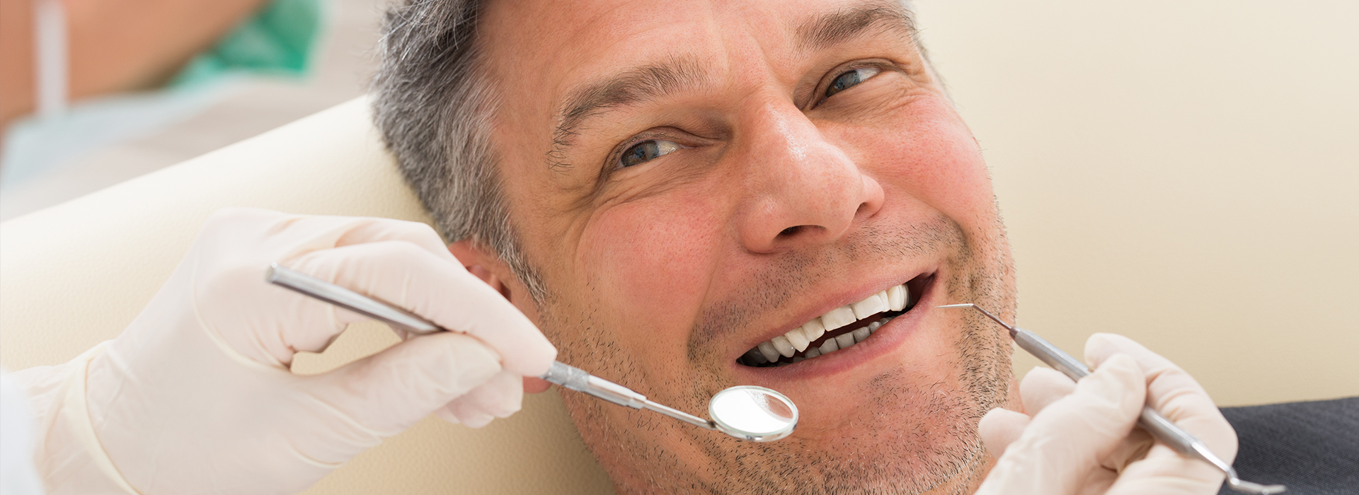 A man sitting in a dental chair with a smiling expression while receiving dental care.