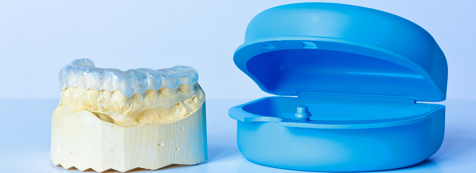 The image shows a blue dental implant crown next to its corresponding metal base, which appears to be a fixture for attaching the crown to an implant in a mouth.