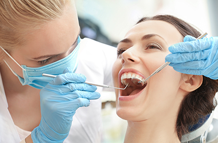 The image shows a dental hygienist performing oral care on a patient s teeth using specialized equipment.